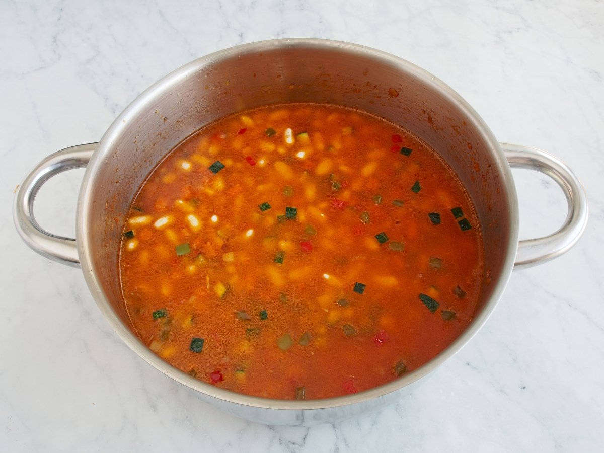Añadir el agua para cocinar las alubias blancas con verduras