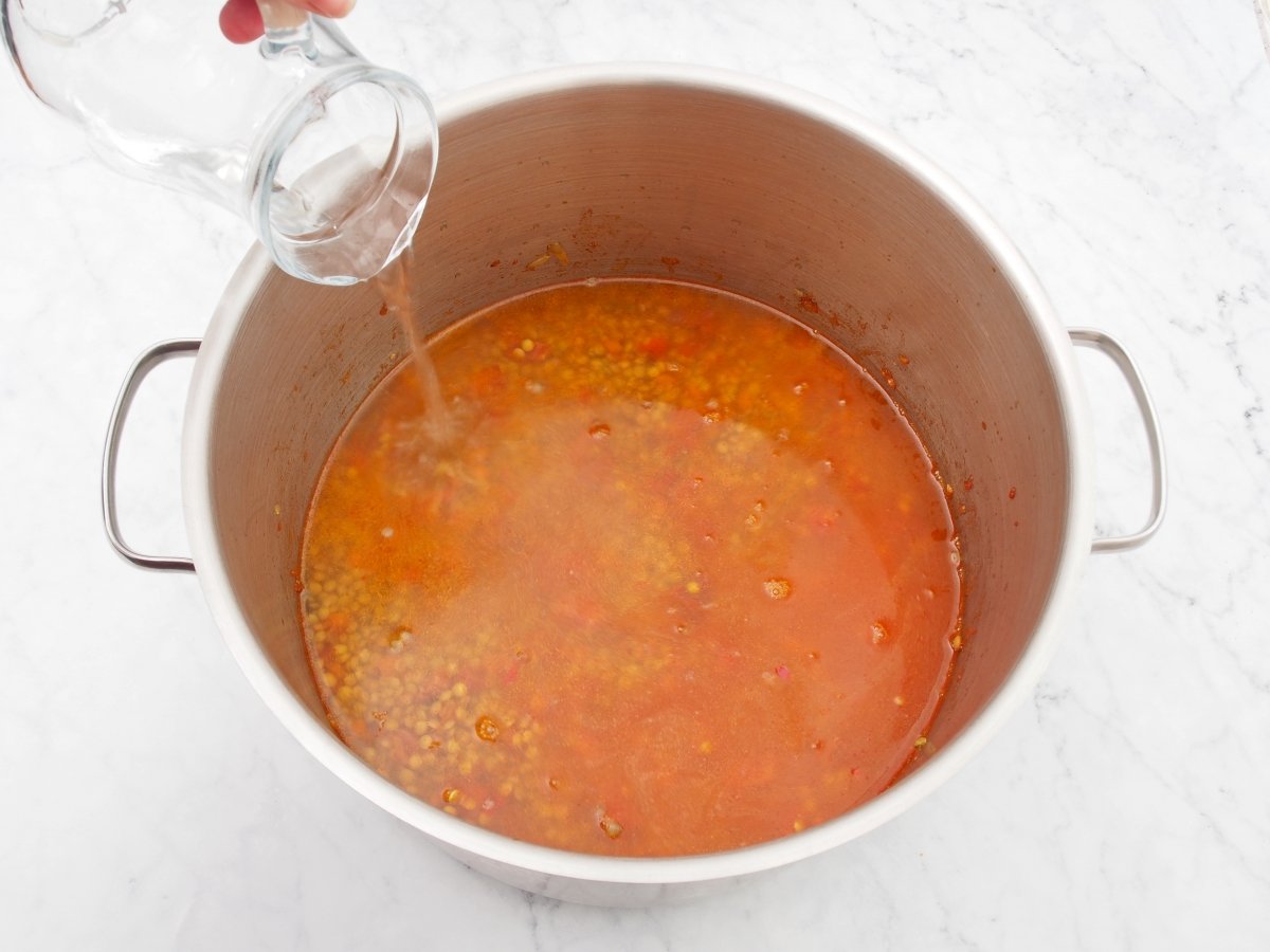 Añadir el agua para cocinar las lentejas con jamón